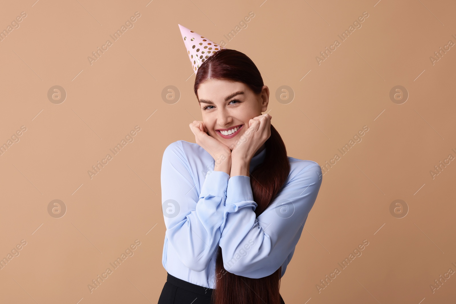 Photo of Happy woman in party hat on beige background