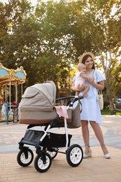 Photo of Happy mother with baby and stroller walking in park