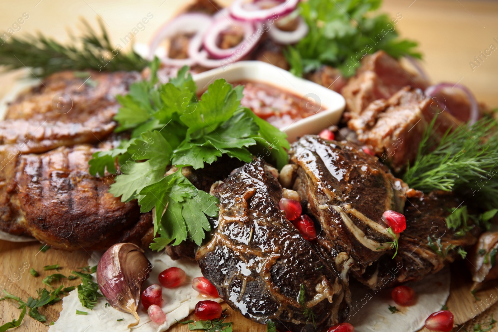 Photo of Delicious roasted meat with herbal on wooden board, closeup