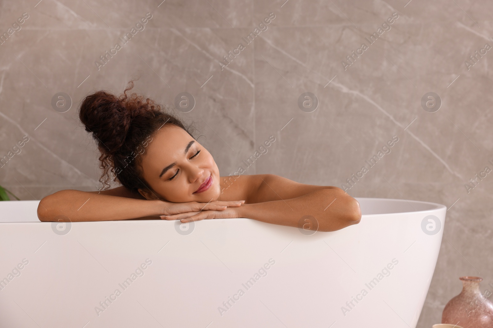 Photo of Beautiful African American woman taking bath indoors