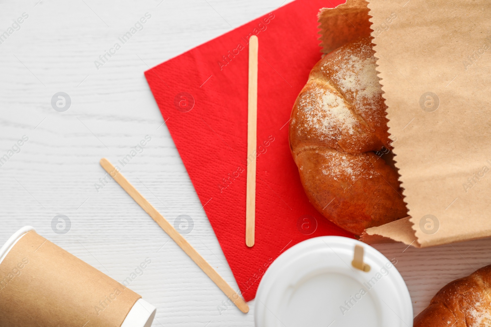 Photo of Flat lay composition with paper bag and pastry on light wooden background. Space for design