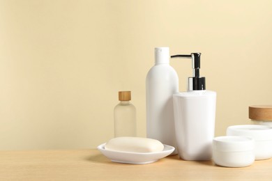 Different bath accessories on wooden table against beige background. Space for text