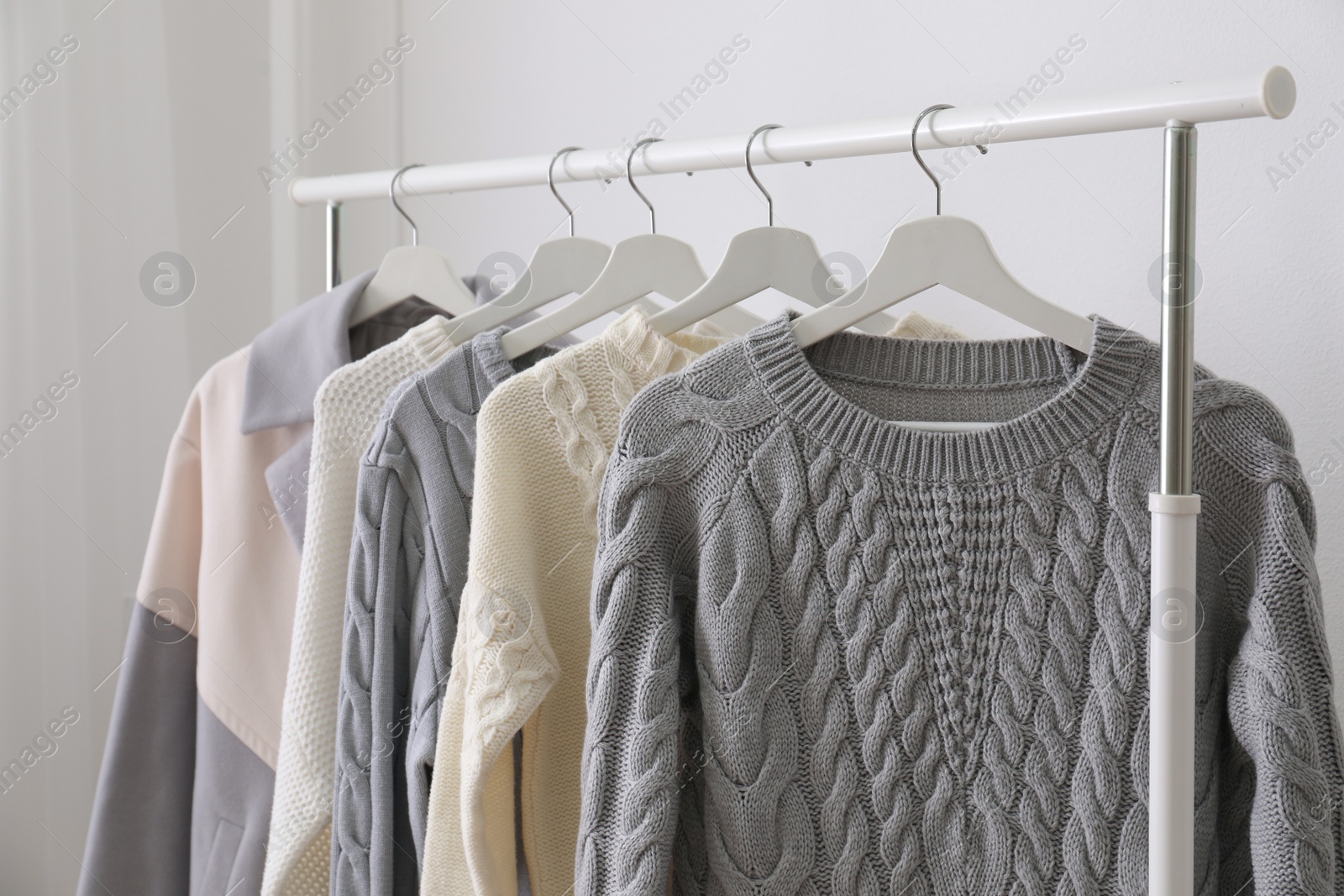 Photo of Rack with stylish warm clothes indoors, closeup