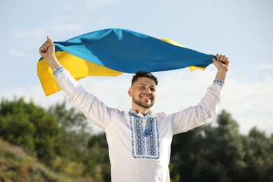 Man in vyshyvanka with flag of Ukraine outdoors