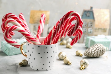Photo of Many sweet candy canes in cup on light table. Traditional Christmas treat
