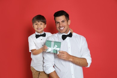 Photo of Man receiving gift for Father's Day from his son on red background