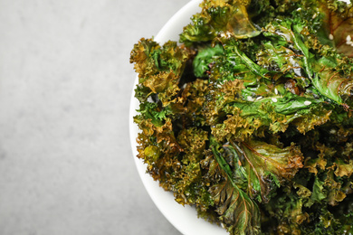 Tasty baked kale chips on grey table, closeup. Space for text