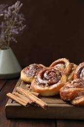 Tasty cinnamon rolls, sticks and nuts on wooden table