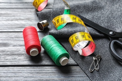 Set of tailoring accessories and fabric on wooden background