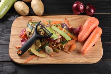 Photo of Peels of fresh vegetables and peeler on dark wooden table, above view