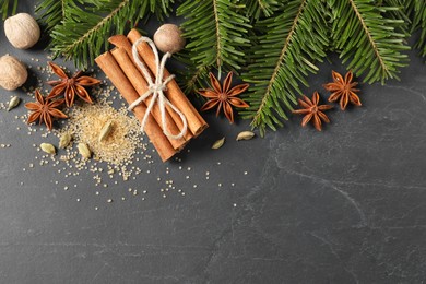 Different spices, nuts and fir branches on gray table, flat lay. Space for text