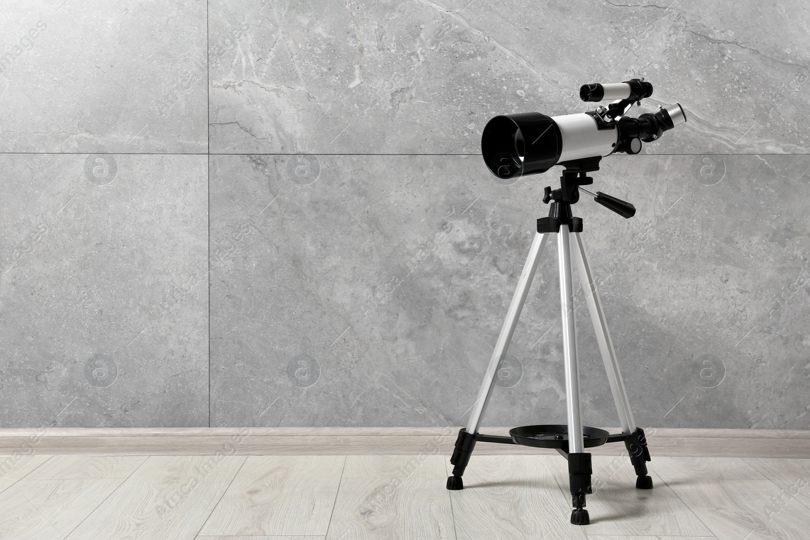 Photo of Tripod with modern telescope near grey wall. Space for text