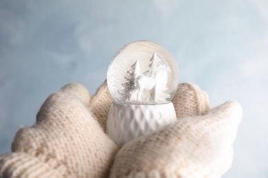 Woman holding empty snow globe on color background, closeup