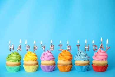 Birthday cupcakes with burning candles on blue background. Space for text