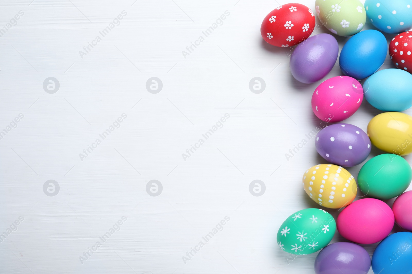 Photo of Bright painted eggs on white wooden table, flat lay with space for text. Happy Easter