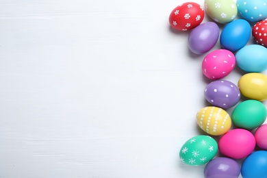 Photo of Bright painted eggs on white wooden table, flat lay with space for text. Happy Easter