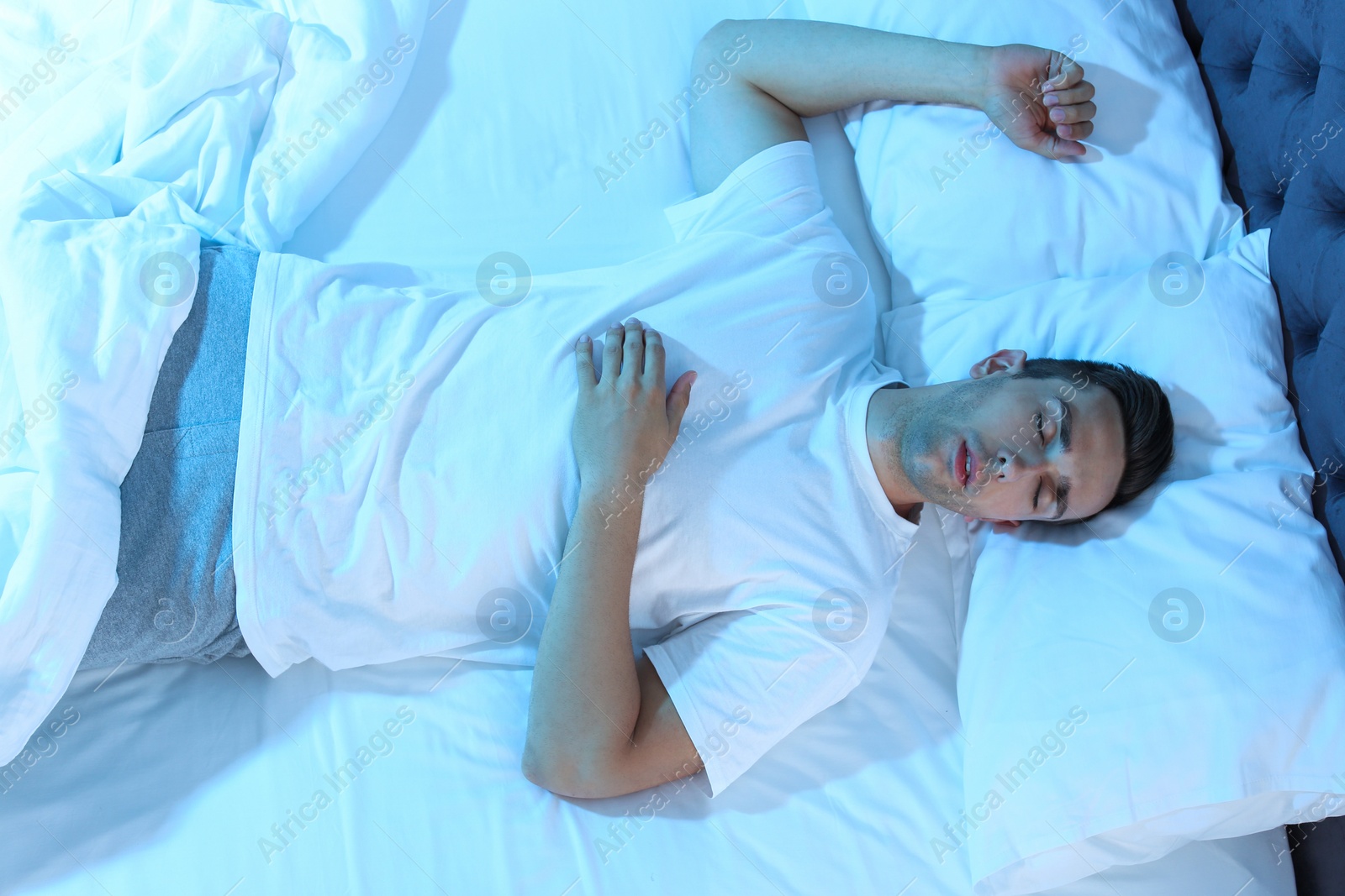 Photo of Young man sleeping in bed at night, top view