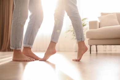 Photo of Couple dancing barefoot at home, closeup. Floor heating system