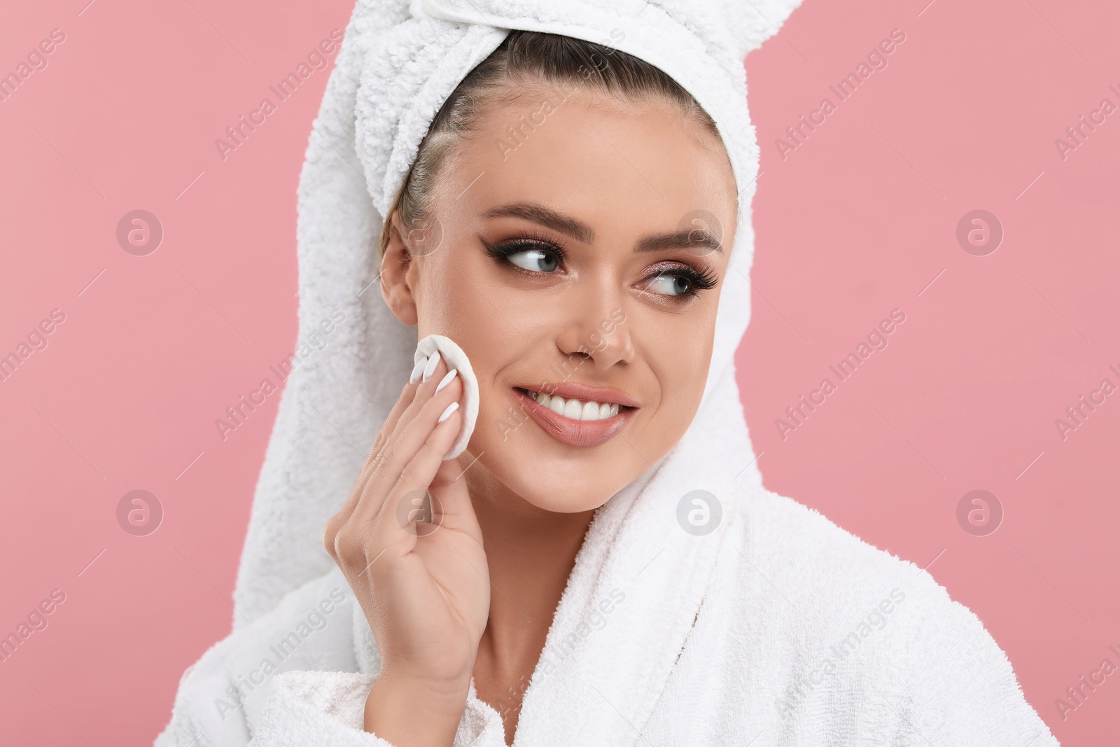 Photo of Beautiful woman removing makeup with cotton pad on pink background