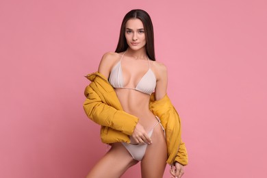 Photo of Young woman in stylish bikini and jacket on pink background