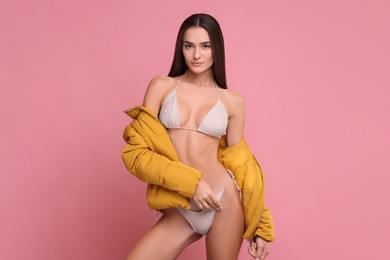 Young woman in stylish bikini and jacket on pink background