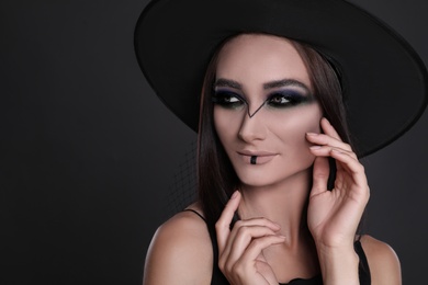 Mysterious witch wearing hat on black background, closeup