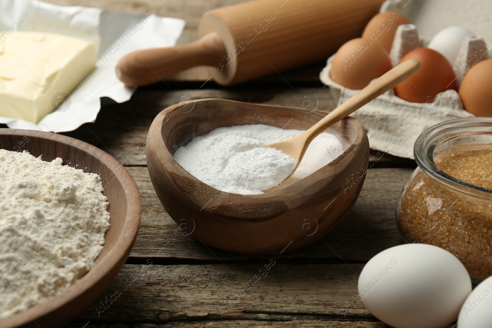 Photo of Ingredients for making dough and rolling pin on wooden table, closeup