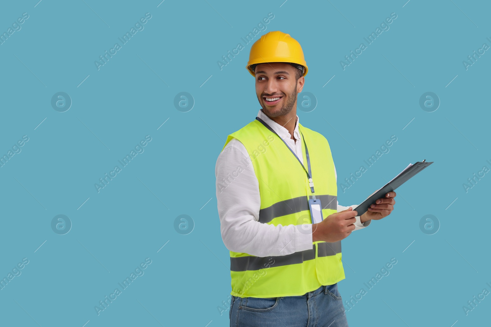 Photo of Engineer in hard hat holding clipboard on light blue background, space for text
