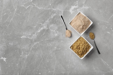 Bowls and spoons with different types of flour on light background