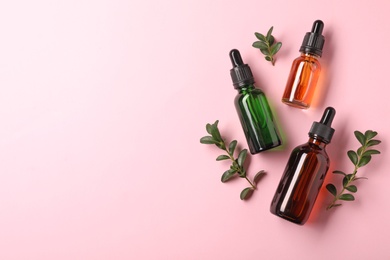 Bottles of essential oils on color background, flat lay with space for text. Cosmetic products