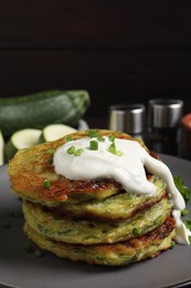 Delicious zucchini fritters with sour cream on plate