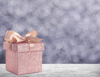 Image of Beautiful gift box on stone table against blurred background, bokeh effect. Space for text