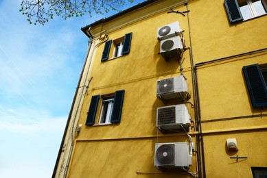 Photo of Beautiful house with air conditioners on wall against blue sky, low angle view