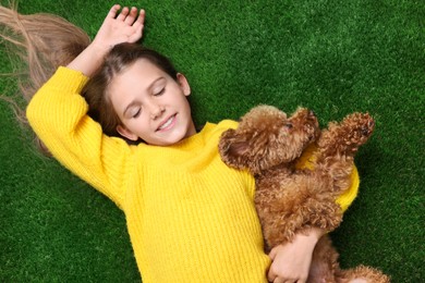 Photo of Little child with cute puppy on green grass, top view. Lovely pet
