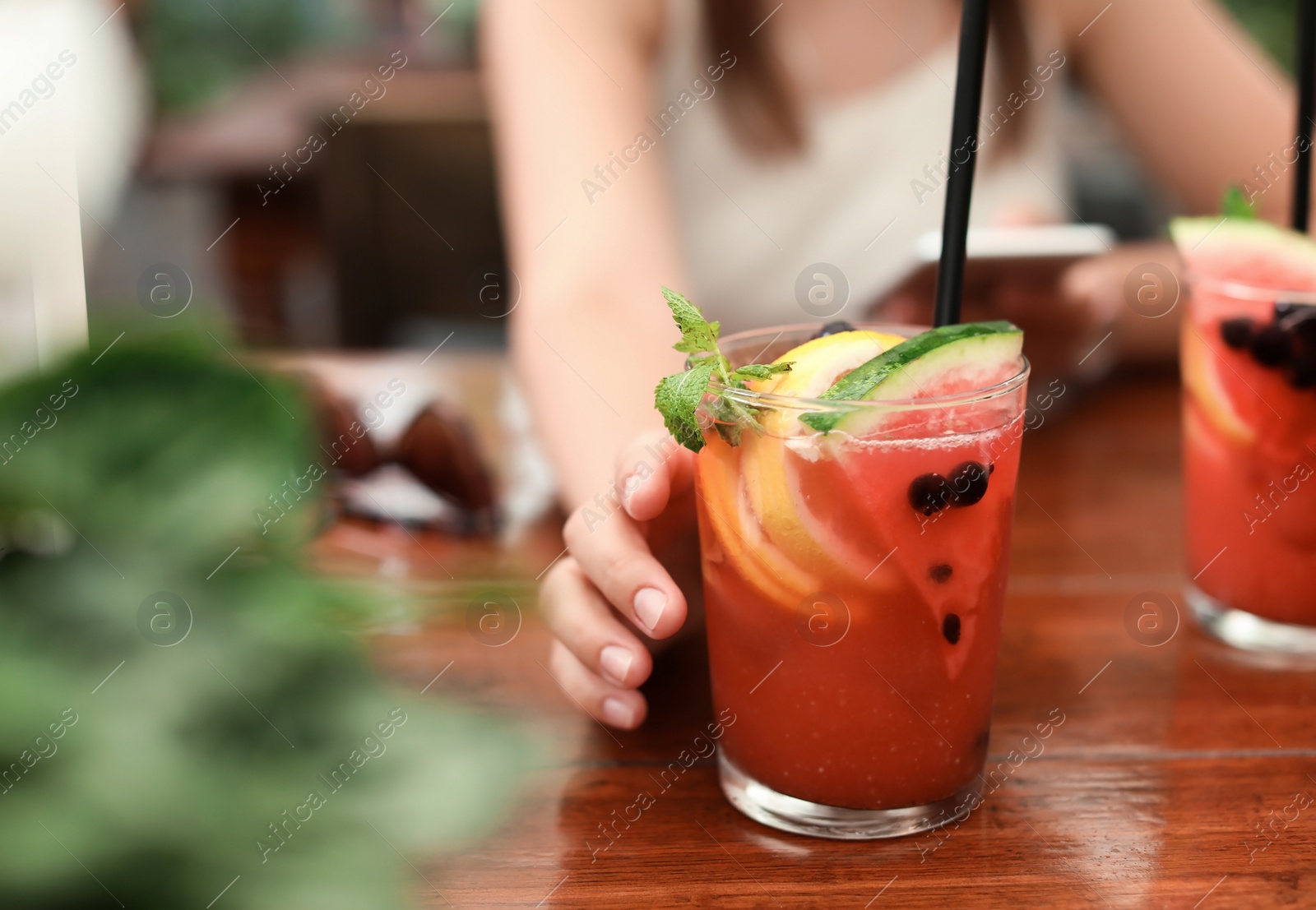 Photo of Woman with glass of tasty lemonade at table, closeup