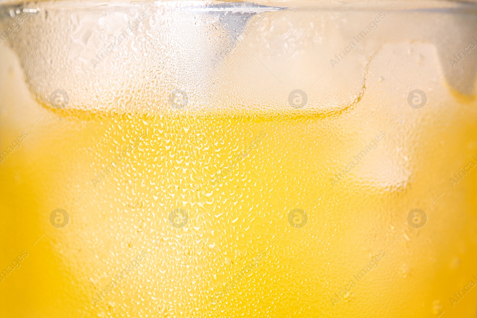 Photo of Glass of refreshing drink with ice cubes on light background, closeup