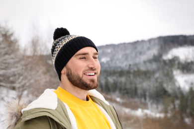 Photo of Happy man against snowy mountains. Winter vacation