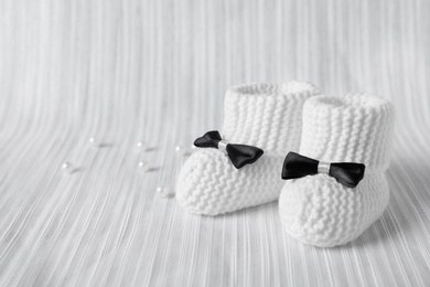 Handmade baby booties on light plaid. Space for text