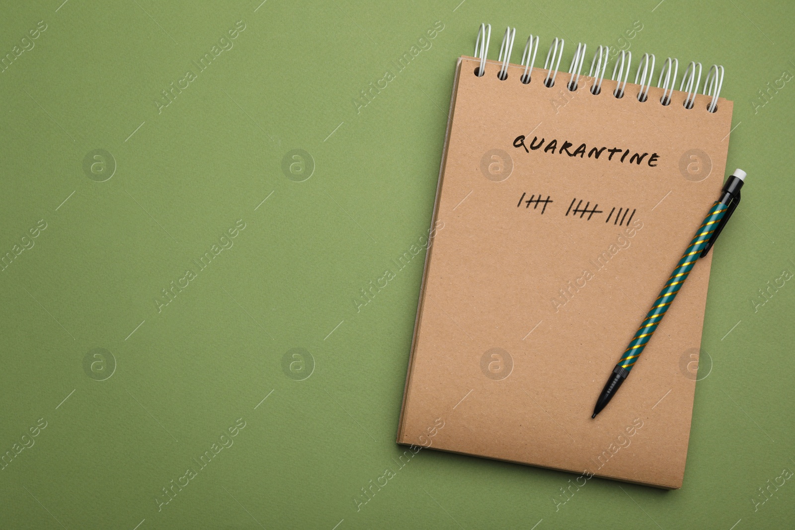 Image of Notebook and pencil on green background, top view with space for text. Counting days of quarantine during coronavirus outbreak