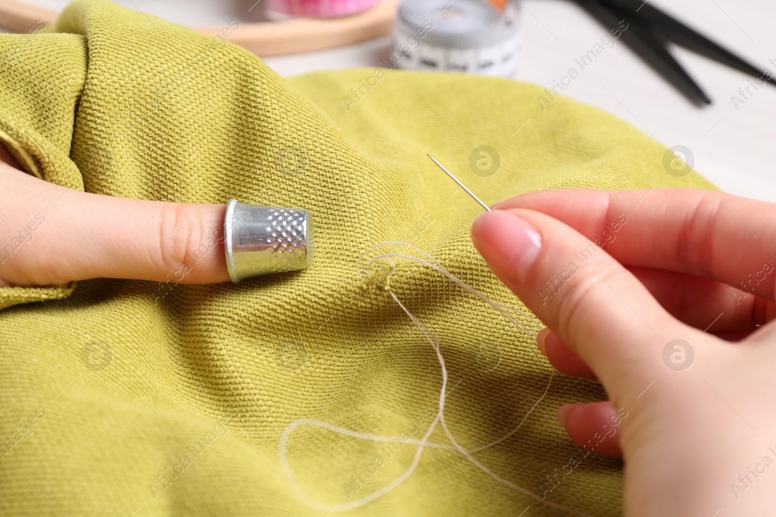 Photo of Woman with sewing needle and thread embroidering on cloth, closeup