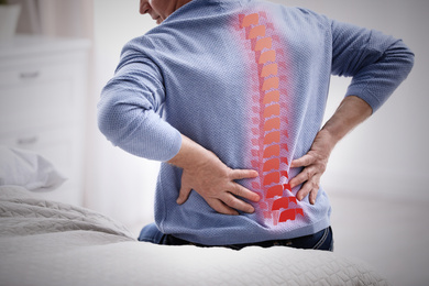 Senior man suffering from pain in back at home, closeup 