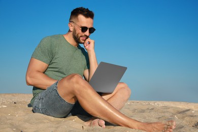 Man working with modern laptop on beach