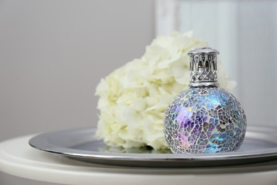 Photo of Stylish catalytic lamp with hydrangea on table in room closeup. Cozy interior