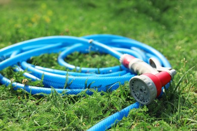 Photo of Watering hose with sprinkler on green grass outdoors, closeup