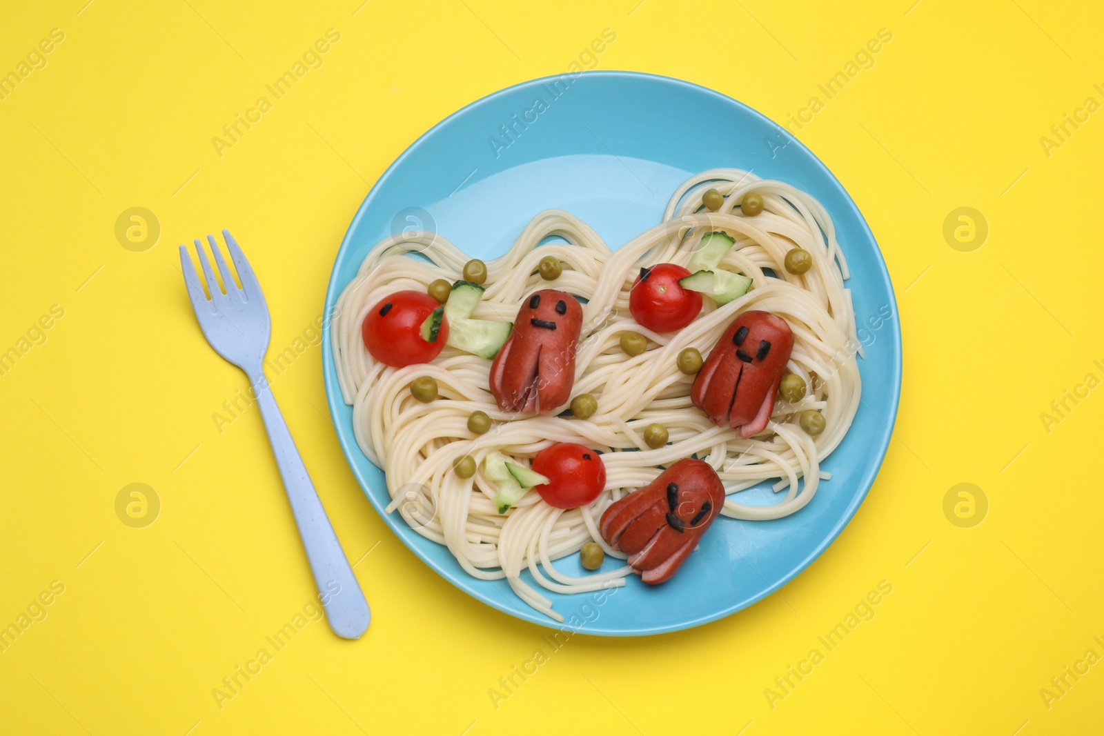 Photo of Creative serving for kids. Plate with cute octopuses made of sausages, pasta and vegetables on yellow table, flat lay