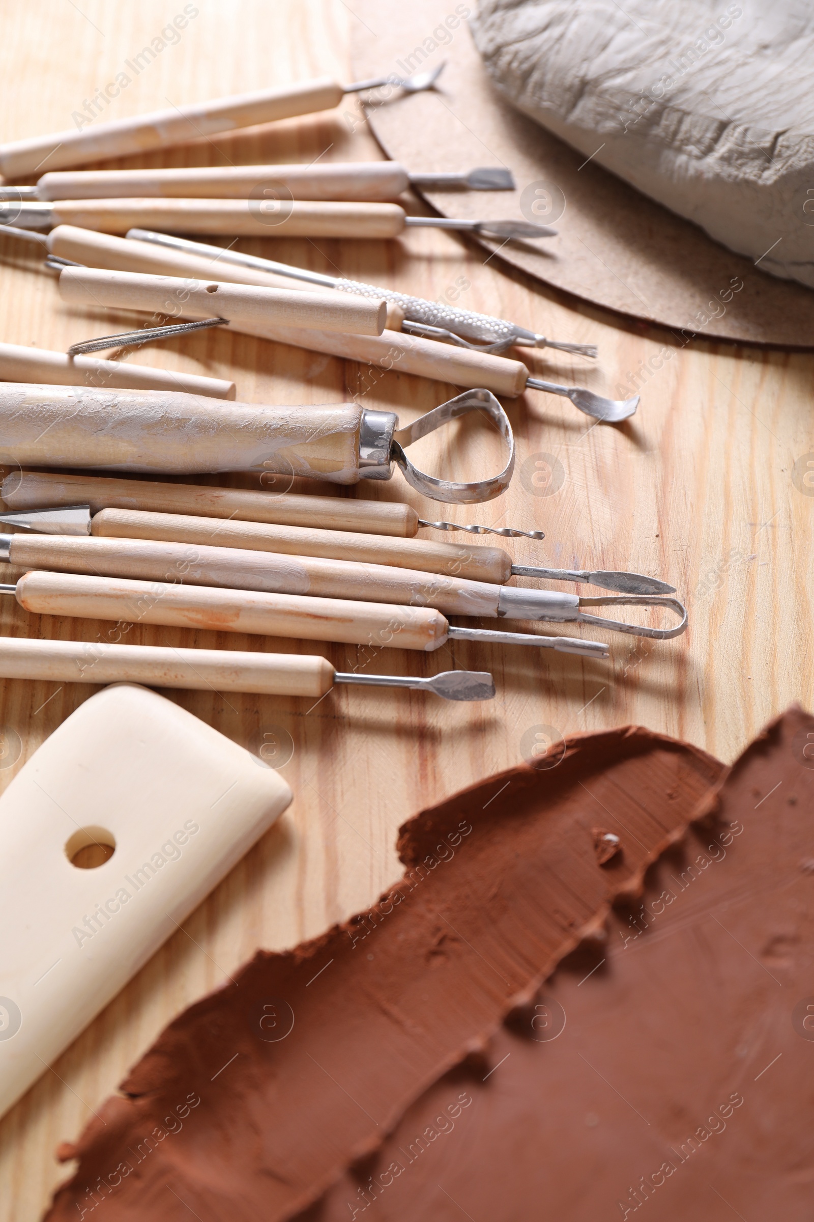 Photo of Set of different clay crafting tools on wooden table, closeup