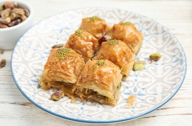 Photo of Delicious baklava with pistachio nuts on white wooden table, closeup