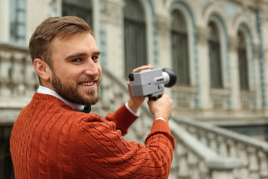 Photo of Young man with vintage video camera outdoors