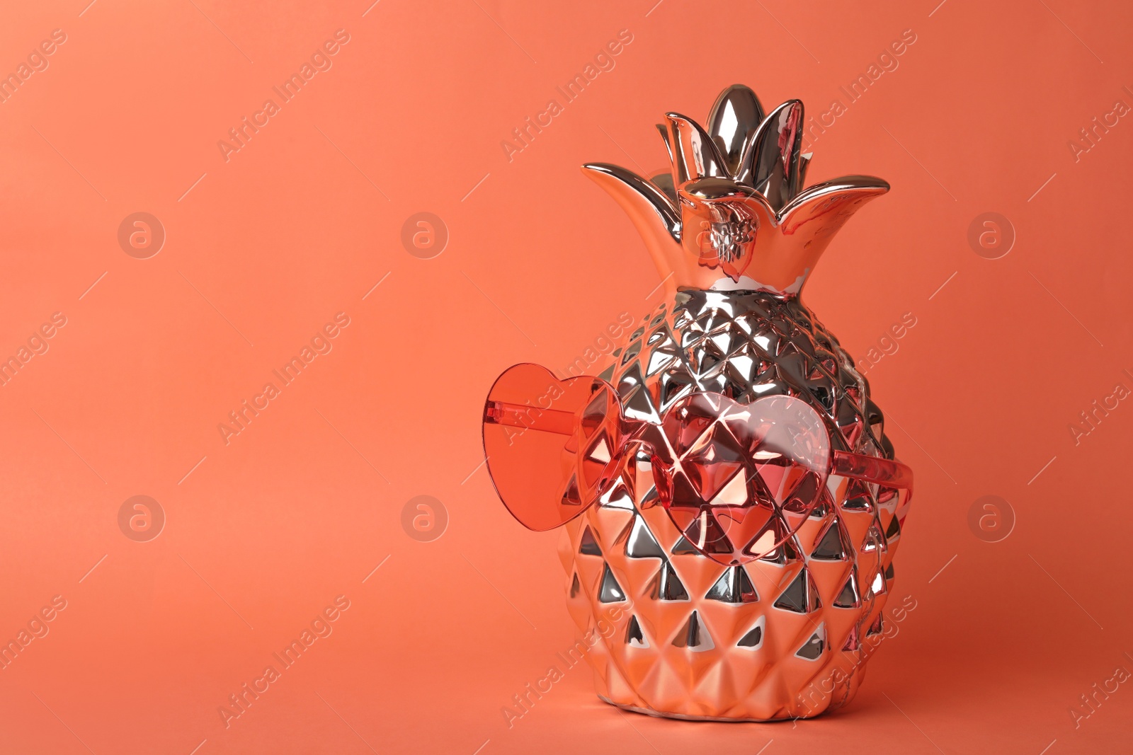 Photo of Heart shaped coral sunglasses and decorative pineapple on orange background. Space for text