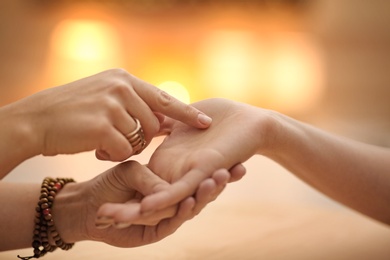 Chiromancer reading lines on woman's palm at table, closeup